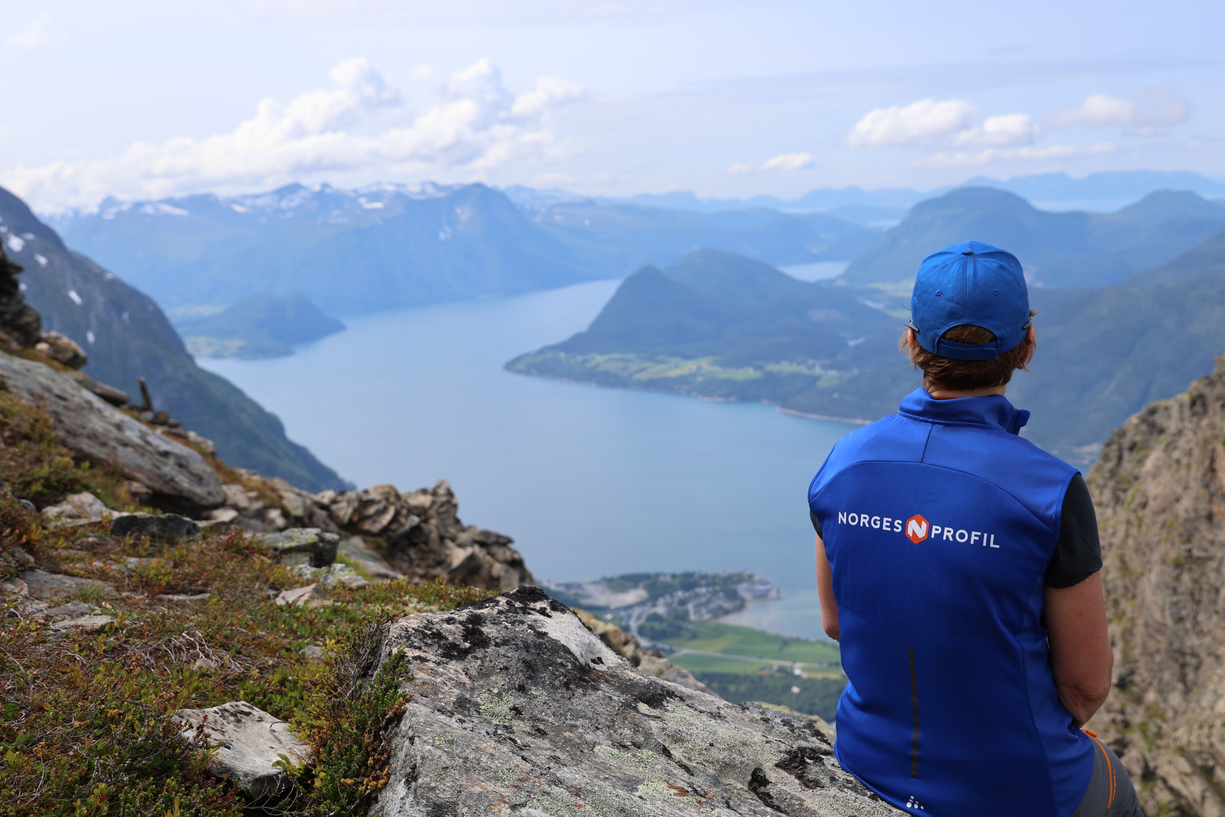 Ansatt i Norgesprofil-vest sitter på en fjelltopp og ser utover fjorden