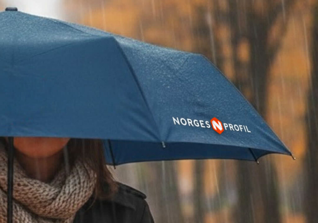 Marineblå paraply med trykt NorgesProfil-logo i høstregn