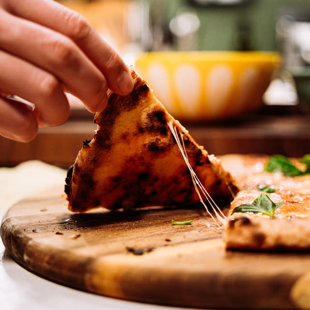 Pizzastykke løftes med smeltet ost