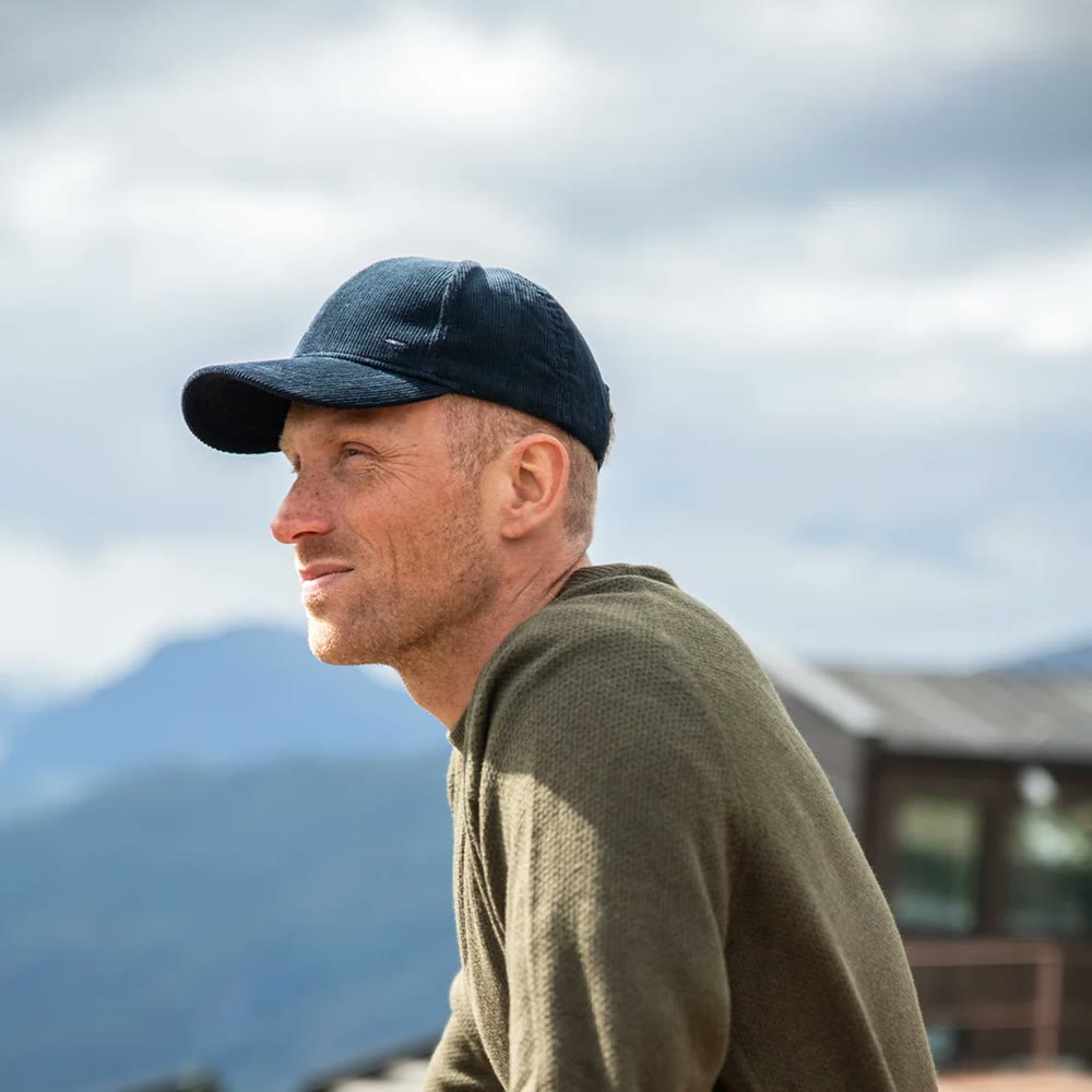Mann i Tufte-caps og ullgenser med fjell i bakgrunnen